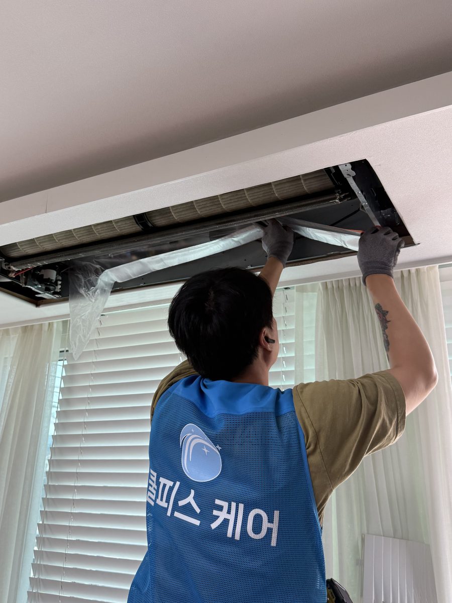 쿨피스케어 작업자가 시스템에어컨을 분해 청소하는 모습